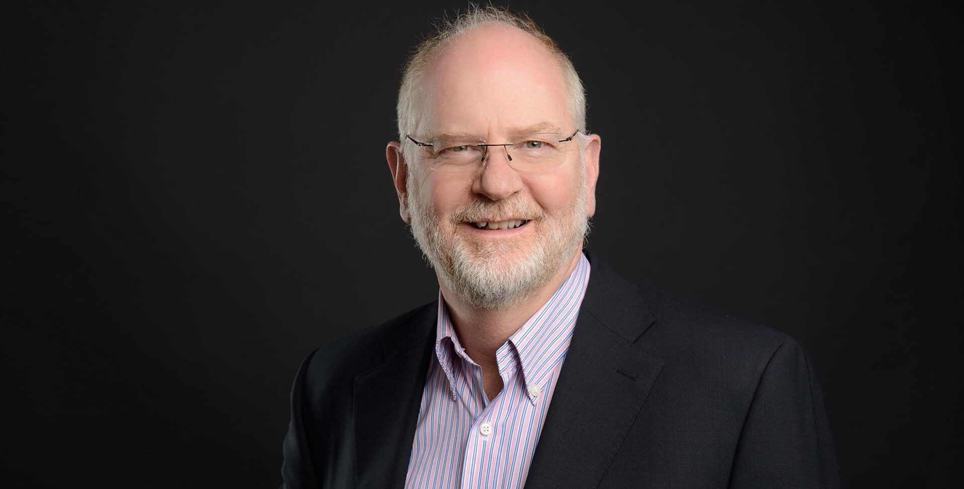 Coffman Engineers Senior VP of Federal Programs Dave Gardner wearing a red striped button-down and black suit jacket.