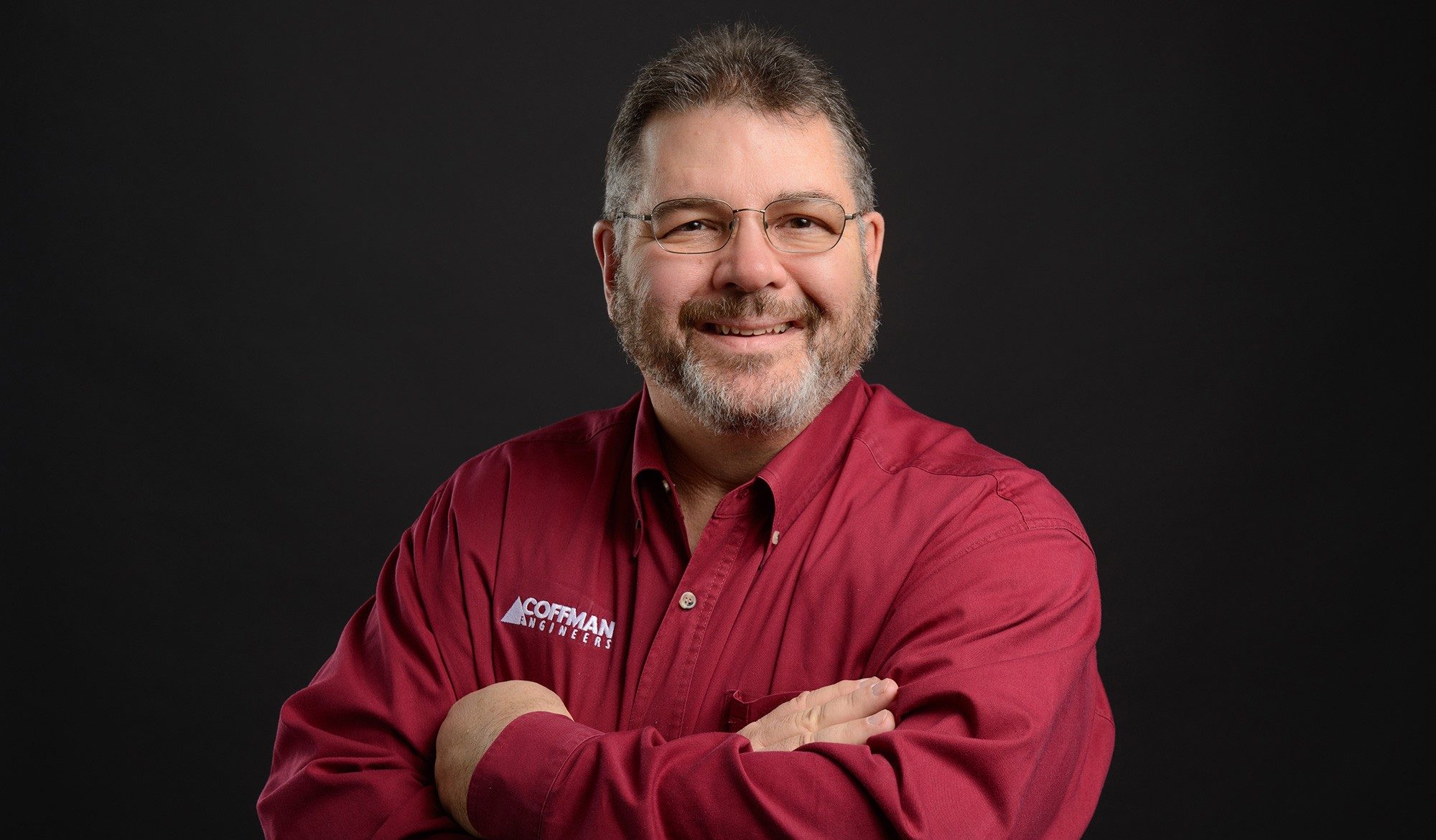 Tom Looney Engineering Principal smiles in front of a black background.