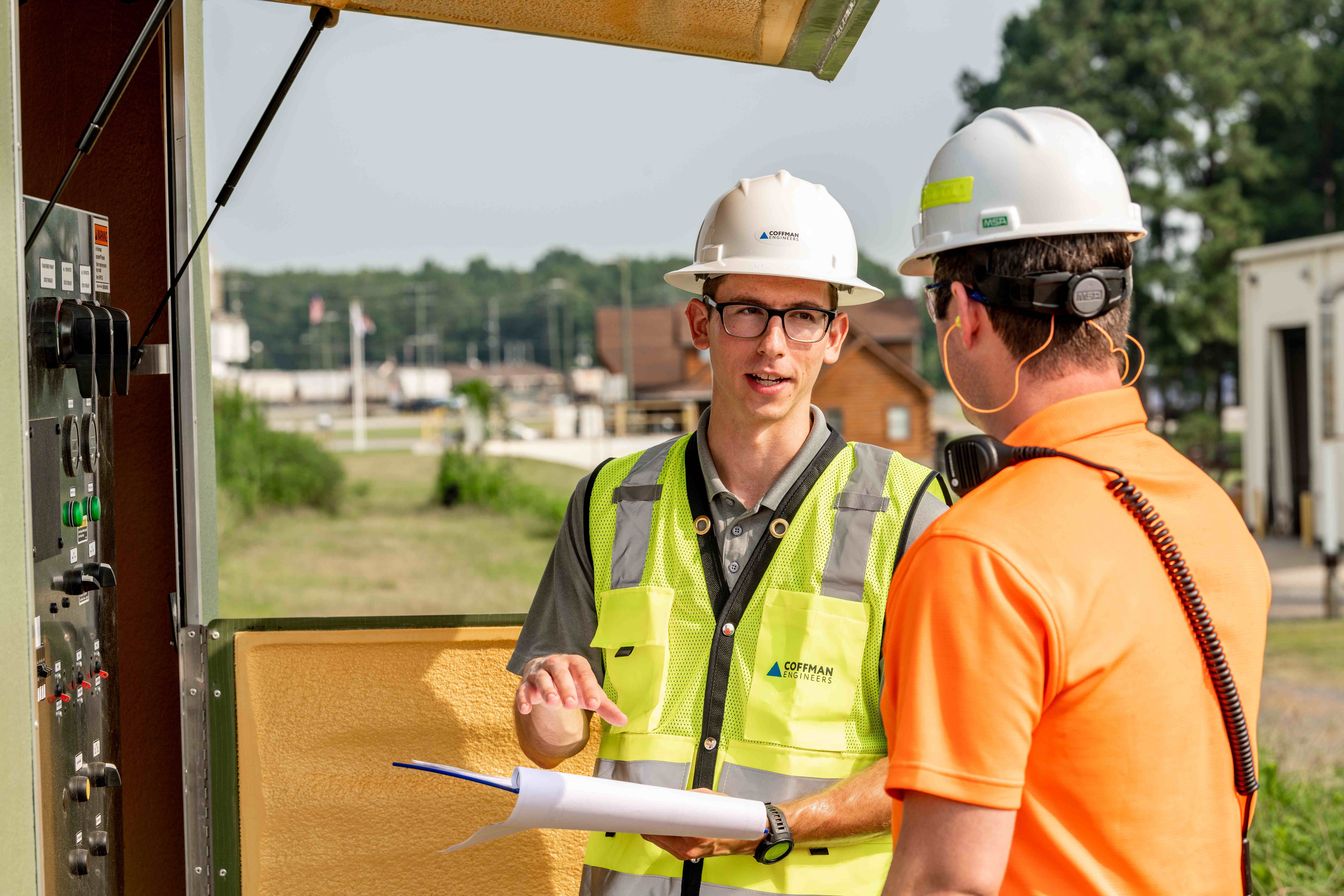 two men wearing full PPE at a site visit holding a clipboard